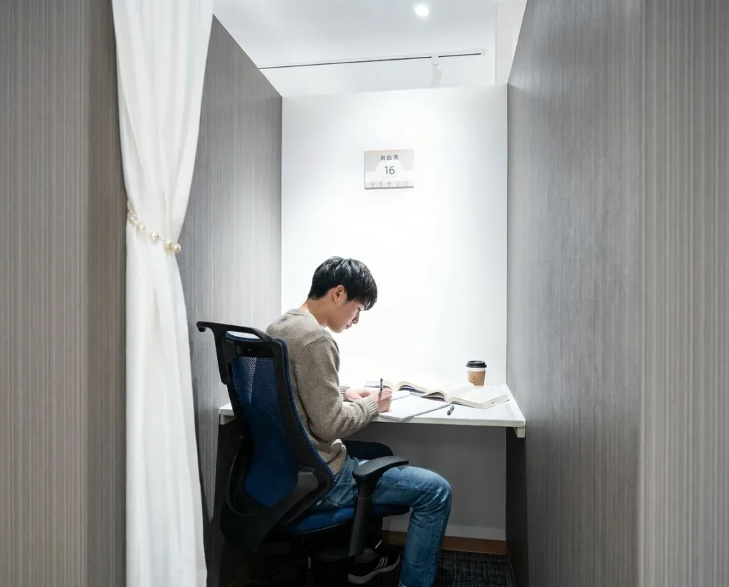 自習室KAKOI 本郷三丁目駅前店のカーテン付き個室ブースで集中して勉強する男性